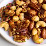 A bowl of freshly roasted Spiced Nuts Mix ready to serve, paired with a cheese board for entertaining.