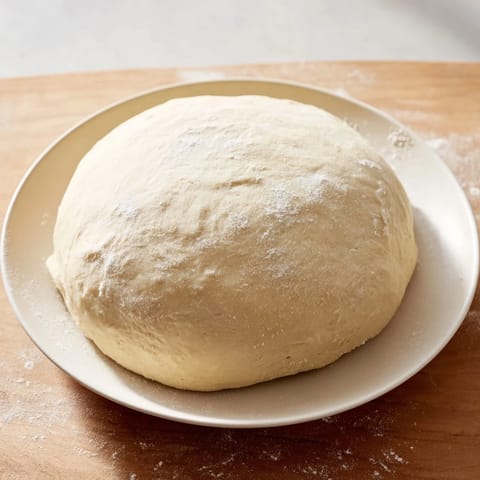 Close-up of freshly kneaded homemade pizza dough, smelling yeasty, ready for the first rise.