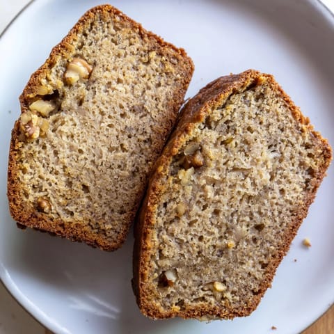 Freshly baked Simple Banana Bread loaf, ready to slice and enjoy with a comforting drink.