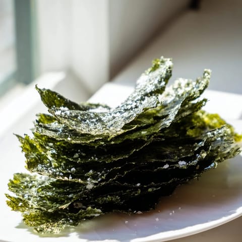 Golden-brown roasted seaweed chips with a light crunch, perfect for a savory vegan snack.  