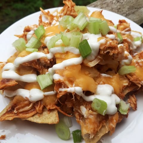 Hearty Buffalo Chicken Nachos piled high with spicy chicken, bubbling cheese, and crisp veggies on a game day platter.