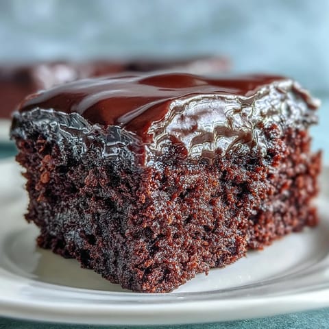 Slice of Easy Chocolate Fudge Cake served with fresh raspberries and a dollop of whipped cream.