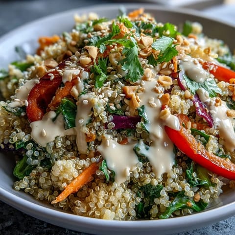 Close-up of Thai Coconut Quinoa Bowl with colorful vegetables and creamy peanut dressing drizzled.
