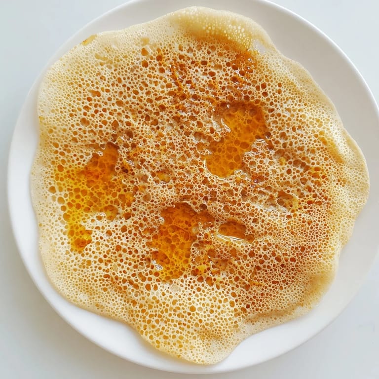 Fluffy, porous Moroccan Baghrir pancakes fresh from the pan showcase their signature honeycomb texture, perfect for breakfast.