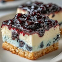 Creamy no-bake lemon blueberry cheesecake bars with bright fruit swirls.